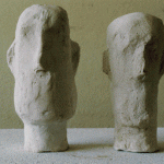 Zwei abstrakte Gipsköpfe mit grober Textur, nebeneinander auf hellem Untergrund | Two abstract plaster heads with rough texture, side by side on light surface