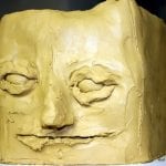 Quaderförmiger Tonklotz mit grob modelliertem menschlichem Gesicht, geschlossene Augen | Rectangular clay block with roughly modeled human face, closed eyes