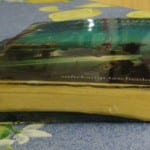 Suhrkamp Taschenbuch in Kunstharz eingegossen, auf gemustertem Stoff | Suhrkamp paperback encased in resin, resting on patterned fabric