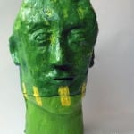 Grün bemalte Pappmaché-Skulptur eines menschlichen Kopfes mit gelben Akzenten | Green painted papier-mâché sculpture of a human head with yellow accents