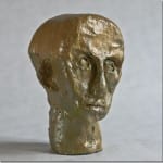 Bronzefarbener Skulpturenkopf eines Mannes, grob modelliert, neutraler Ausdruck | Bronze-colored sculpted male head, roughly modeled, neutral expression