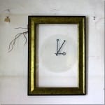 Goldener Bilderrahmen mit minimalistischen Uhrzeigern hinter Glas an verwitterter Wand | Golden picture frame with minimalist clock hands behind glass on weathered wall