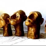 Fünf goldene Keramikköpfe mit expressiven Gesichtern auf weißem Untergrund | Five golden ceramic heads with expressive faces on white surface