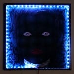 Leuchtkasten mit blauem LED-Rahmen: dunkles Kindergesicht mit roten Lippen und Augen | LED light box with blue frame: dark child face with red lips and glowing eyes