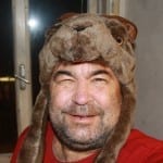 Mann mit brauner Tier-Kostümmütze lacht, roter Pullover | Man wearing brown animal costume hat laughing, red sweater