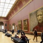 Museumssaal mit Besuchern, roten Wänden und großem Porträtgemälde eines kahlen Gesichts | Museum hall with visitors, red walls and large portrait painting of a bald face