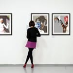 Frau betrachtet drei gerahmte digitale Kunstwerke mit weiblichen Figuren in Galerie | Woman viewing three framed digital artworks with female figures in gallery