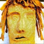 Gelb-orangefarbenes Wachsrelief eines Gesichts mit Blätterkranz, geschlossene Augen | Yellow-orange wax relief of a face with leaf crown, closed eyes
