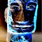 Blau beleuchtete Eisskulptur eines menschlichen Gesichts vor dunklem Hintergrund | Blue illuminated ice sculpture of a human face against dark background