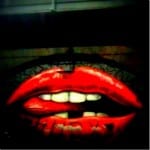 Überdimensionale rote Lippen mit Zähnen, Graffiti an dunkler Wand | Oversized red lips with teeth, graffiti on dark wall