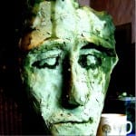 Grünlich patinierter Tonskulptur-Kopf mit ausdrucksstarken Augen, raue Oberflächenstruktur | Greenish patinated clay sculpture head with expressive eyes and rough textured surface