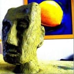 Grobe Tonskulptur eines Gesichts vor Gemälde mit gelber Orange auf Blau | Rough clay face sculpture before painting of yellow orange on blue background