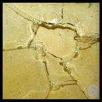 Zerbrochenes Glas mit sternförmigem Einschlagmuster auf gelbem Untergrund | Broken glass with star-shaped impact pattern on yellow background