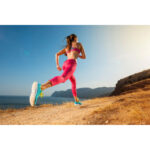 Frau in pinkem Sport-Outfit läuft auf trockenem Küstenpfad mit Meerblick | Woman in pink sportswear running on dry coastal trail with sea view