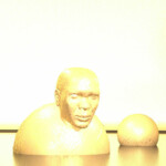 Goldener 3D-gerenderter Männerkopf mit Kugel auf reflektierender Fläche | Golden 3D-rendered male head bust with sphere on reflective surface